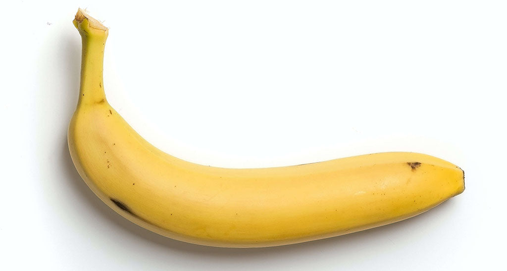 A single ripe banana lays on its side against a white background