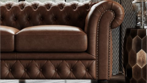 En una Sala de Estar, se muestra la Vista Lateral Derecha de un Lujoso Sofá Loveseat Chesterfield de Cuero Top Grain Parma de 64", color Dark Chocolate, con Marco de Madera y Clavos de Bronce.