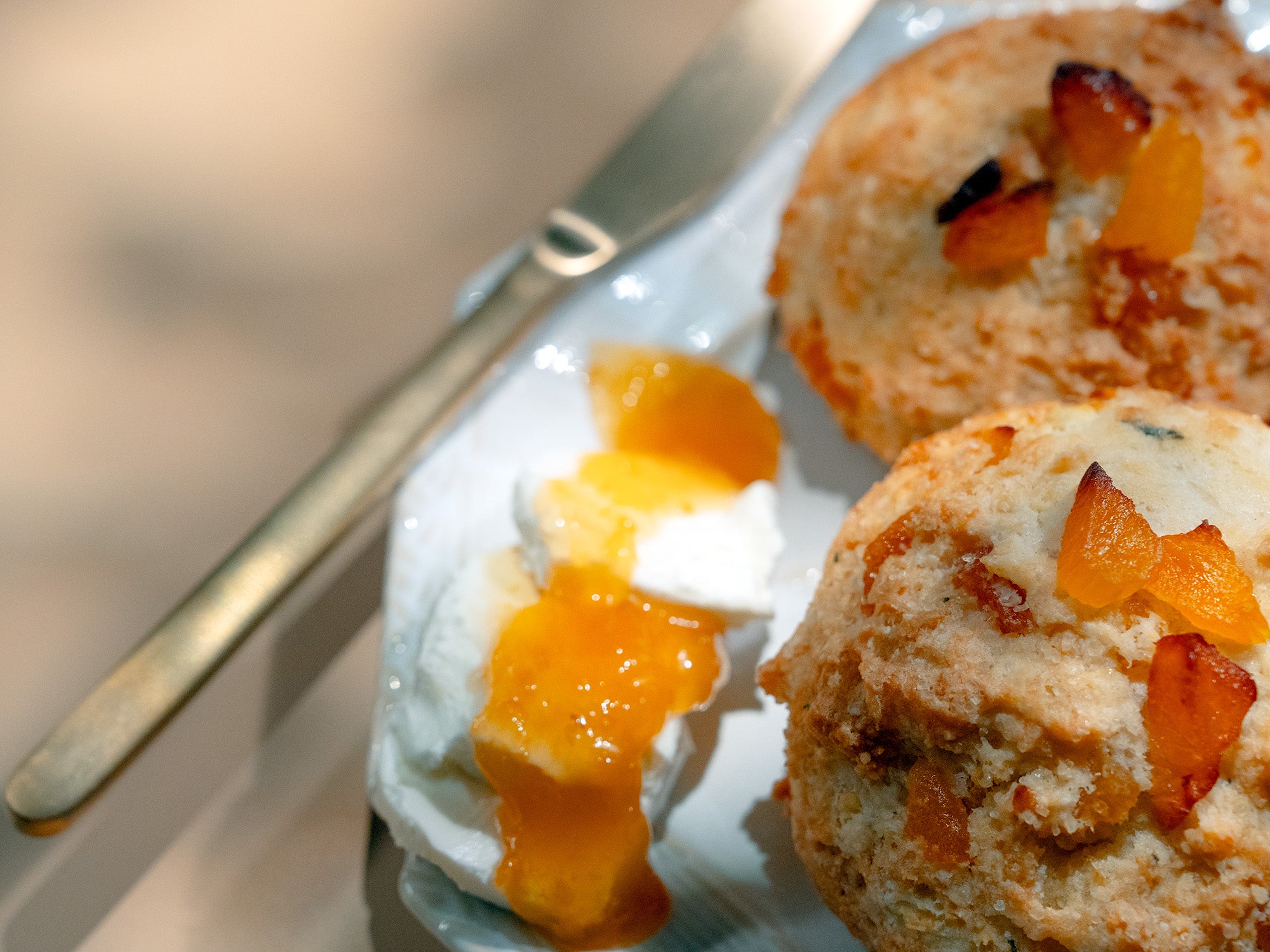 A buttermilk scone topped with apricot, beside a wedge of goat cheese and apricot jam