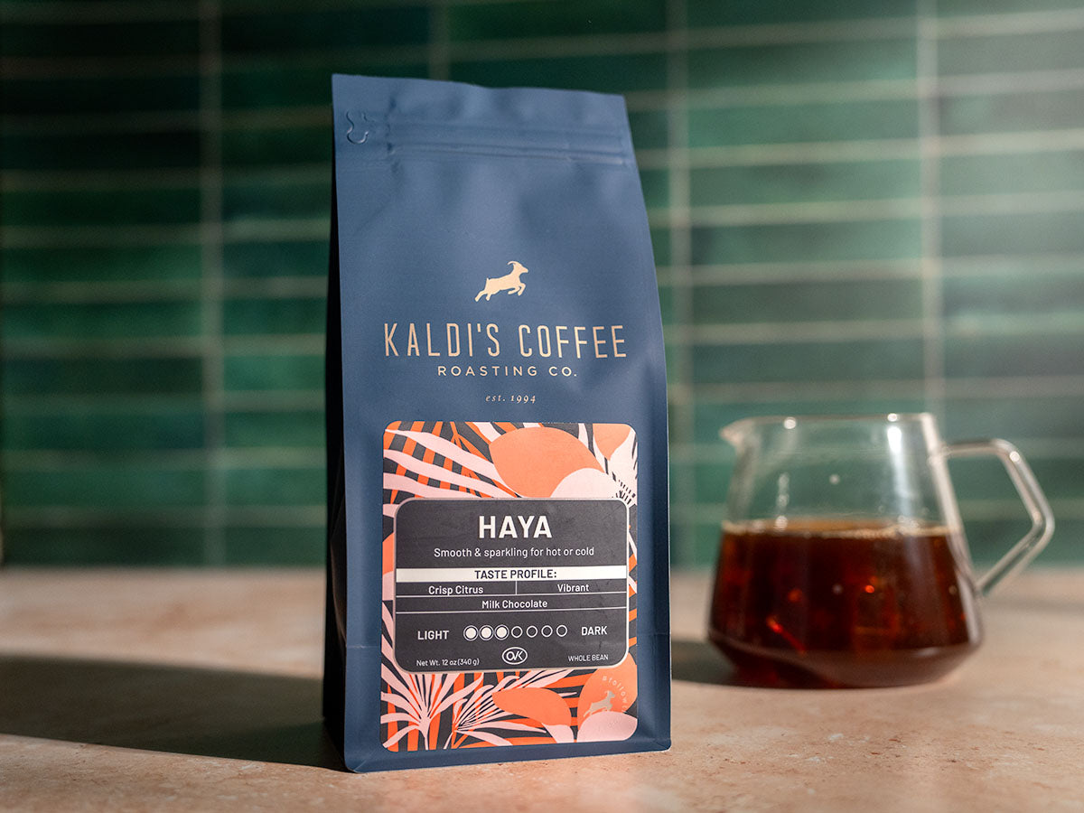 A 12oz bag of Haya sits in front of a fresh brew