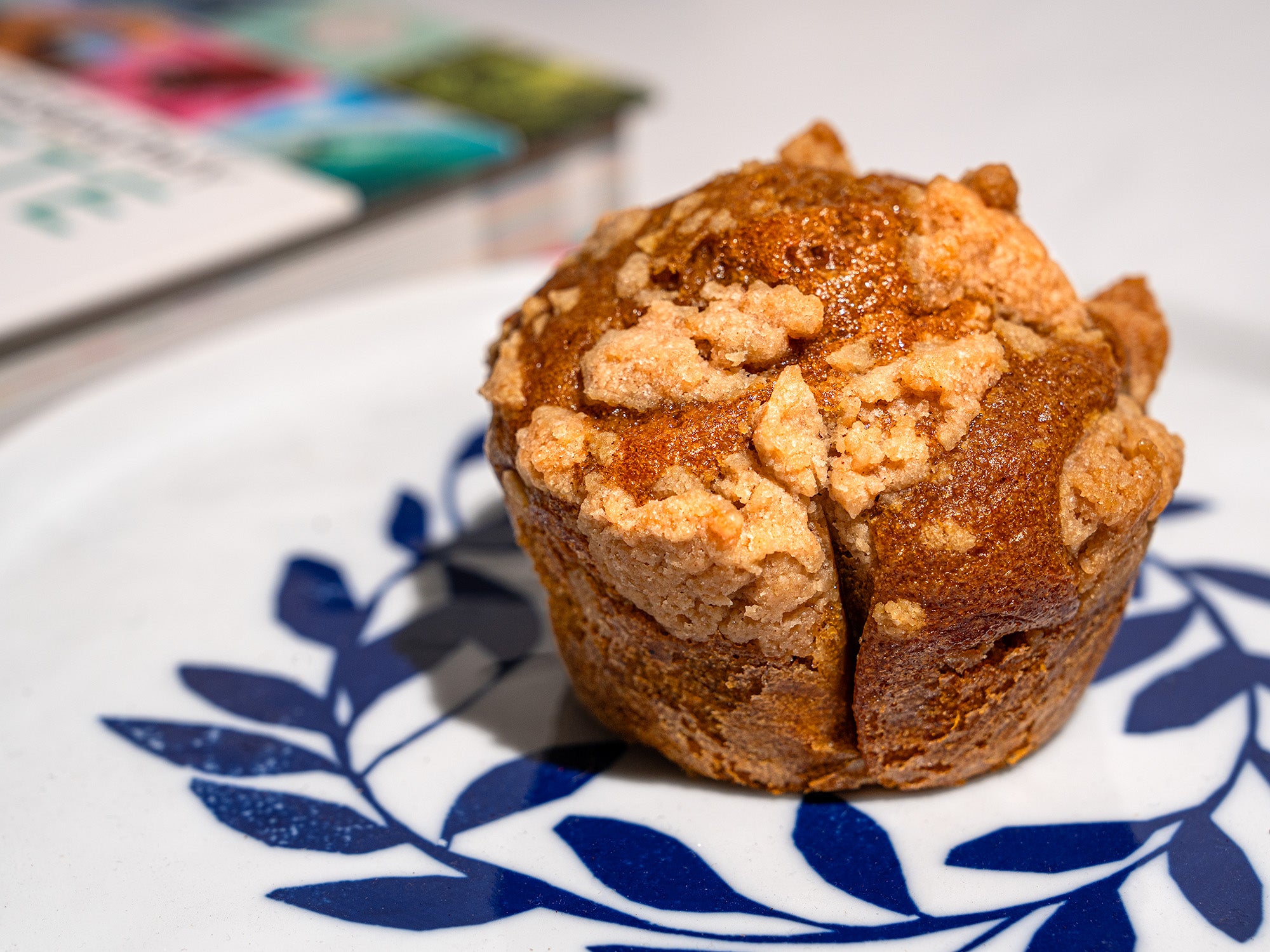 A Pumpkin Muffin with Walnut Streusel sits on a rustic plate