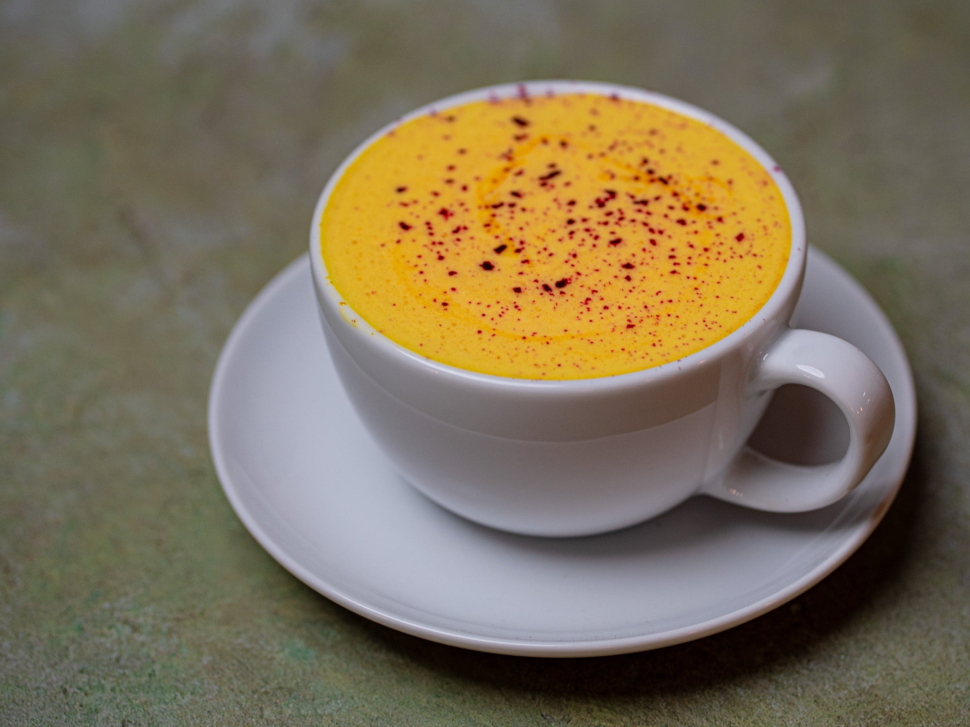 A bright yellow latte with purple sprinkles of dragon fruit powder