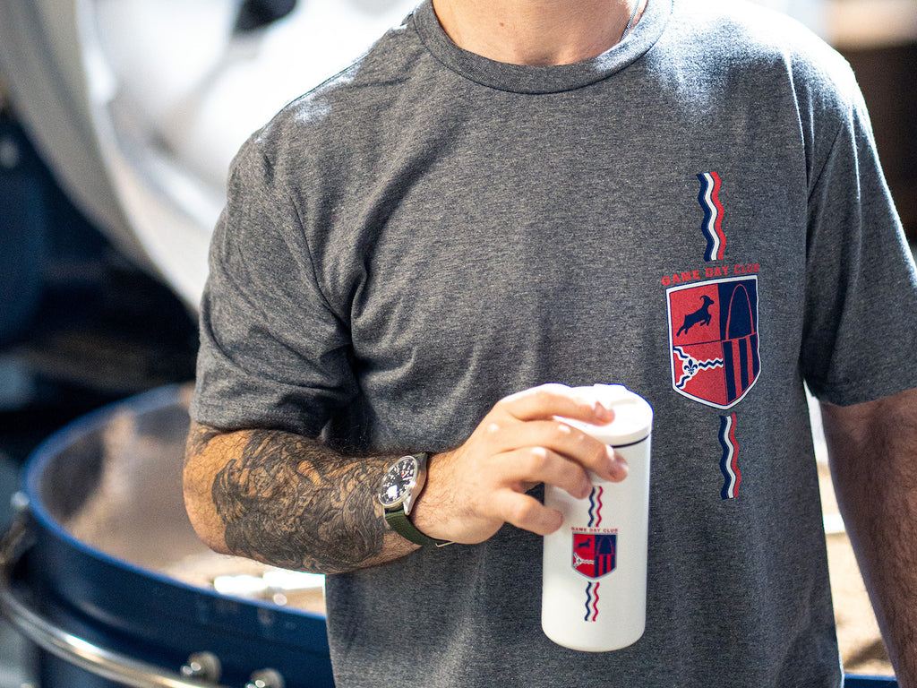 Holding the white Game Day Tumbler v3 while wearing the new Game Day Tee