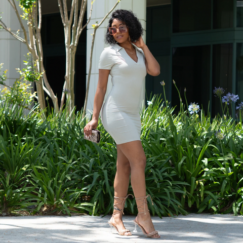 Black female outside wearing a ribbed sage green mini dress,Brown sunglasses and nude lace up heels 