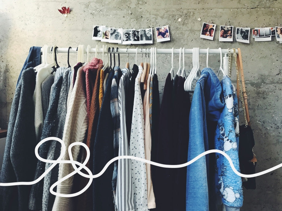 A line of clothing hanging from a metal clothes rail.