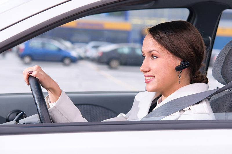 Woman using Bluetooth 5.0 ear piece in car