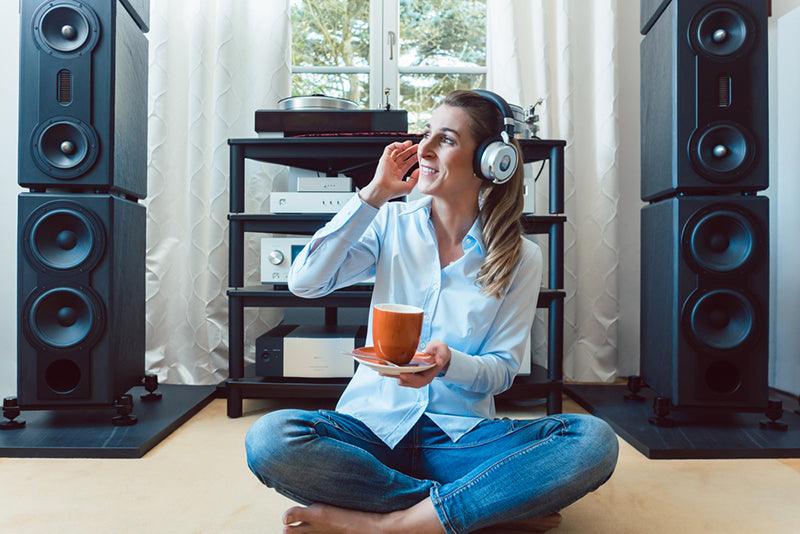 Woman sitting in the floor listen to bluetooth headphones and drinking tea