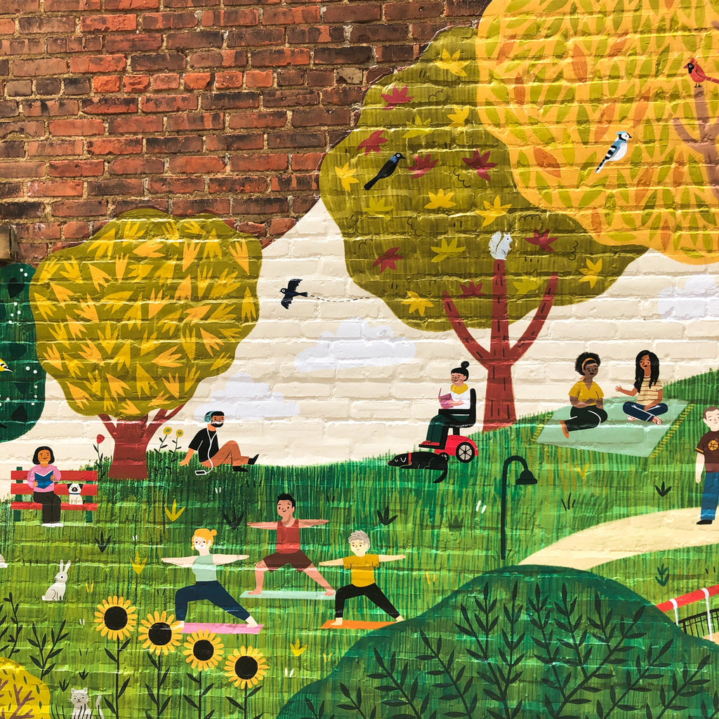 Section of mural with two people sitting on blanket and talking, a person in a motorized wheelchair reading, a person wearing headphones, a person sitting on a bench reading with a dog, a bird flying, three people doing yoga, sunflowers, and a cat hidden behind more leaves