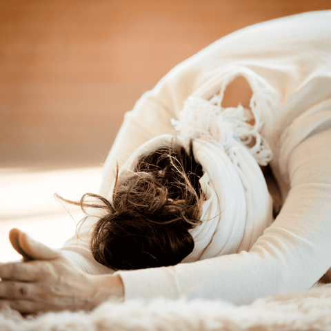 woman dressed in white stretching in kundalini yoga