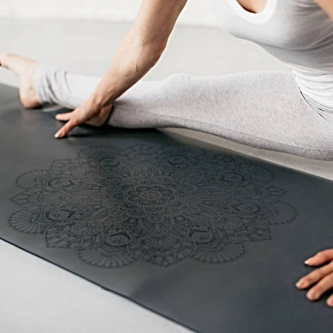 woman stretching her hamstrings on a grey yoga mat