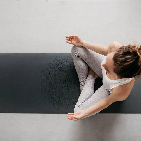 woman in lotus pose on a grey mandala yoga mat