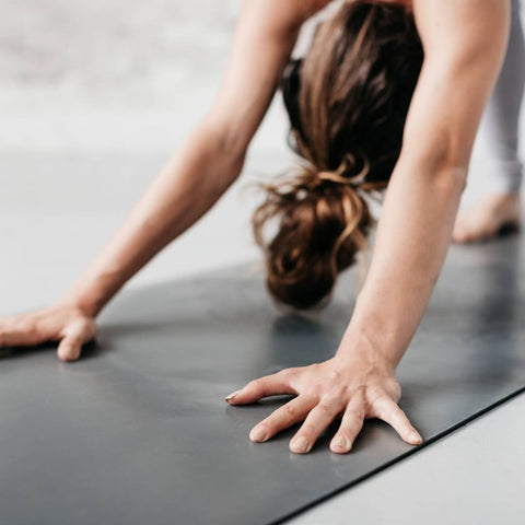 woman in downward dog pose on a grey yoga mat