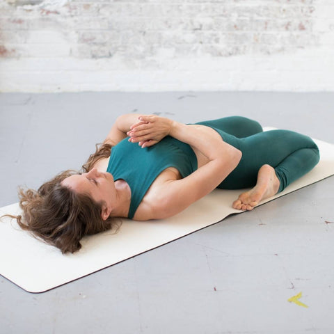 woman doing a yoga pose on a white yoga mat