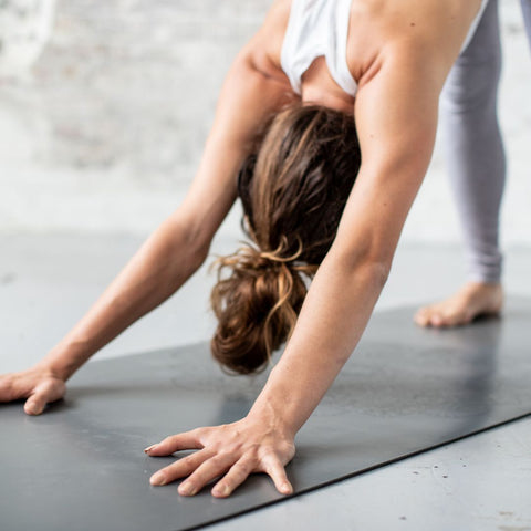 girl in downward dog on a grey yoga mat