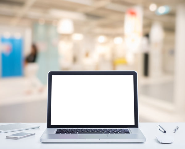 View-from-behind-a-desk-on-top-of-which-sits-a-MacBook-Pro-overlooking-an-open-concept-office-space