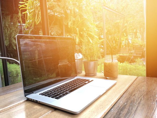 The-sun-shines-through-a-window-onto-a-MacBook-Pro-sitting-on-a-high-desk