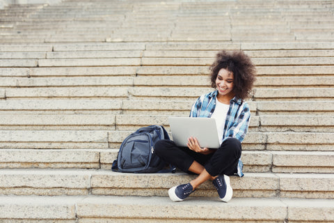 Female-college-student-studying-on-campus-steps-with-a-MacBook
