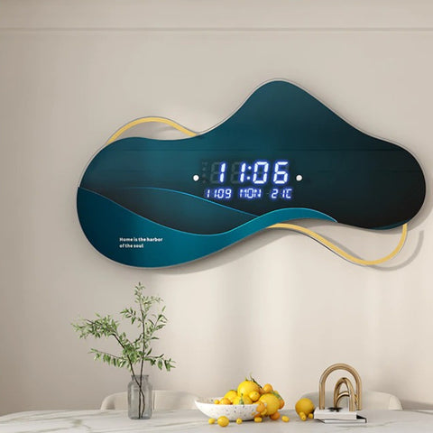 An unusual shaped wall clock called an Asymmetrical Dream Clock. The main component of the clock is greenish blue and is shaped similar to a cloud. The time reads 11:06 and the clock is above a hall table with ornaments on it.