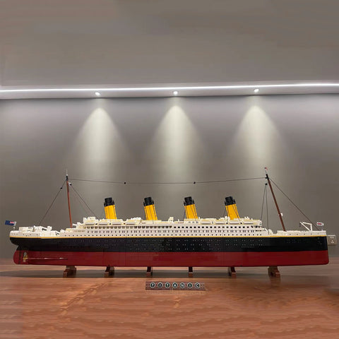 A fully built and complete 9090-piece Lego model kit of Titanic which includes a Lego sign which reads Titanic and is lit up by 3 spotlights.