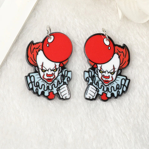 A pair of earrings inspired by the movie IT and Pennywise the Clown. The earrings feature the face of Pennywise holding a red ballon looking very creepy. The earrings are on a white background.