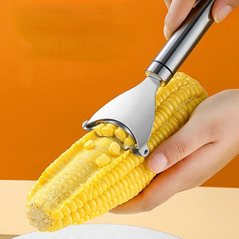 A pair of hands using a silver metal corn stripper which is stripping kernels of a cob of corn