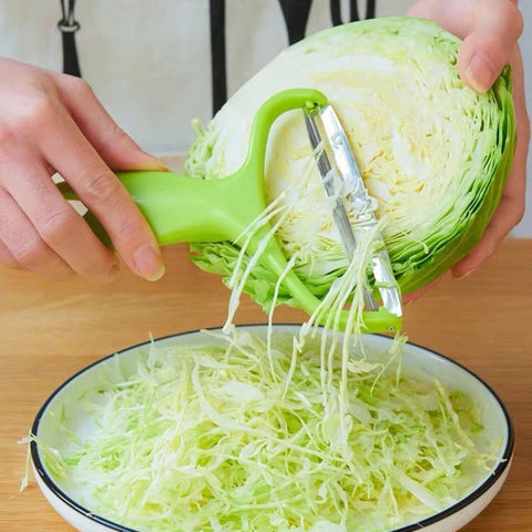 A pair of hands using a green colored cabbage shredder to shred cabbage into a bowl
