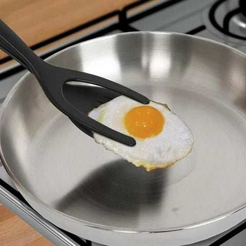 An egg flipper holding a fried egg out of a frying pan preparing to flip it