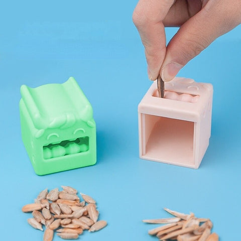 A green and pink sunflower seed peeler with some scattered sunflower seeds in the foreground.