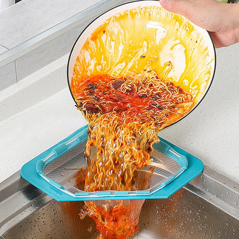 A triangle sink strainer attached to a sink with a hand pouring waste into the strainer off a plate.