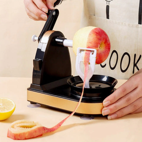 A pair of hands are using a black rotary apple peeler to peel a red apple which is half peeled.