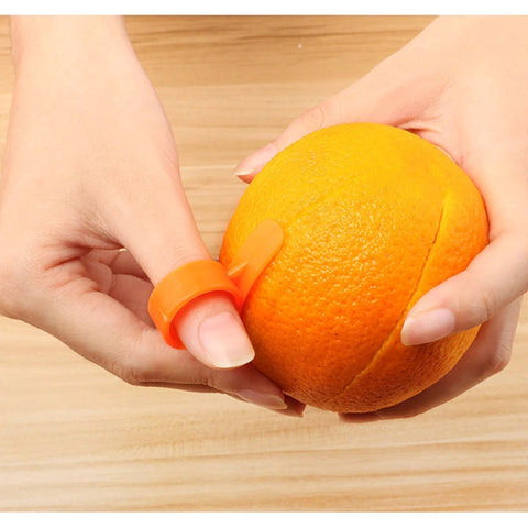 A persons hands wearing an orange peeler ring on their thumb while peeling an orange.