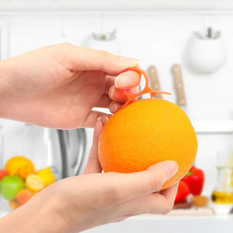 A pair of hands holding an orange and an orange peeler ring preparing to peel an orange.
