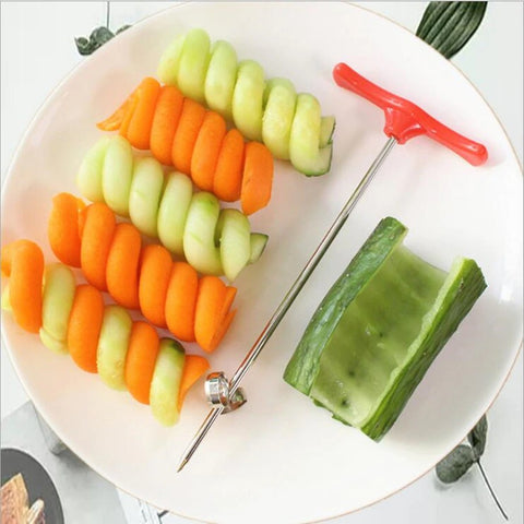 A vegetable spiral cutter on a plate along with cucumber and carrot spirals created by the device.