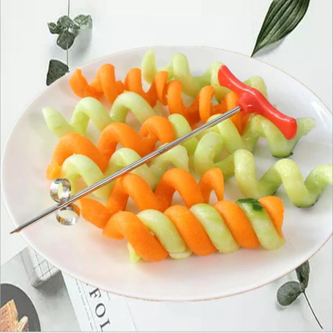 A silver and red vegetable spiral cutter on a plate with vegetable spirals made by the device.