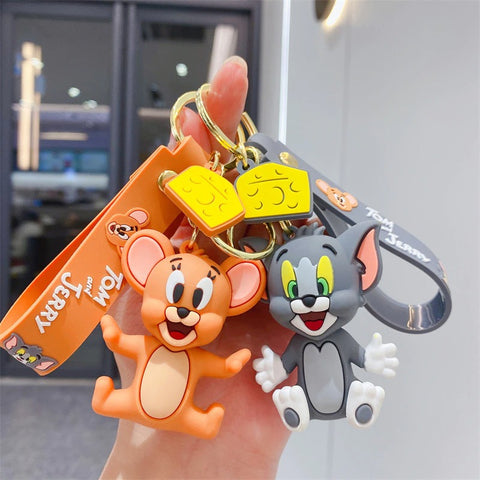 A hand is holding a pair of Tom and Jerry figurine keychains