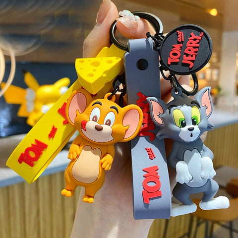 A hand is holding a pair of Tom and Jerry figurine keychains