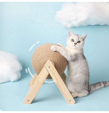 A grey and white kitten playing with a cat scratcher ball spinner which allows felines to sharpen their claws while the ball spins around.