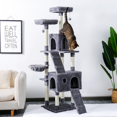 A grey multi level cat tower with a striped cat running down one of the ladders.