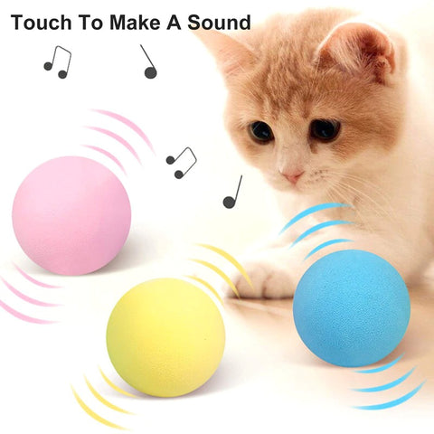 A ginger and white kitten with three different colored interactive smart cat balls with text that says touch to make a sound
