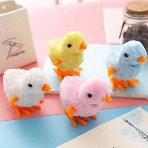 Four windup toy chickens colored white, yellow, pink and blue
