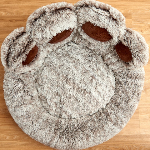 A large grey cat bed shaped like a giant cat paw