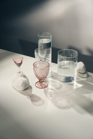 5 empty glass vases of different shapes and colors on a white table
