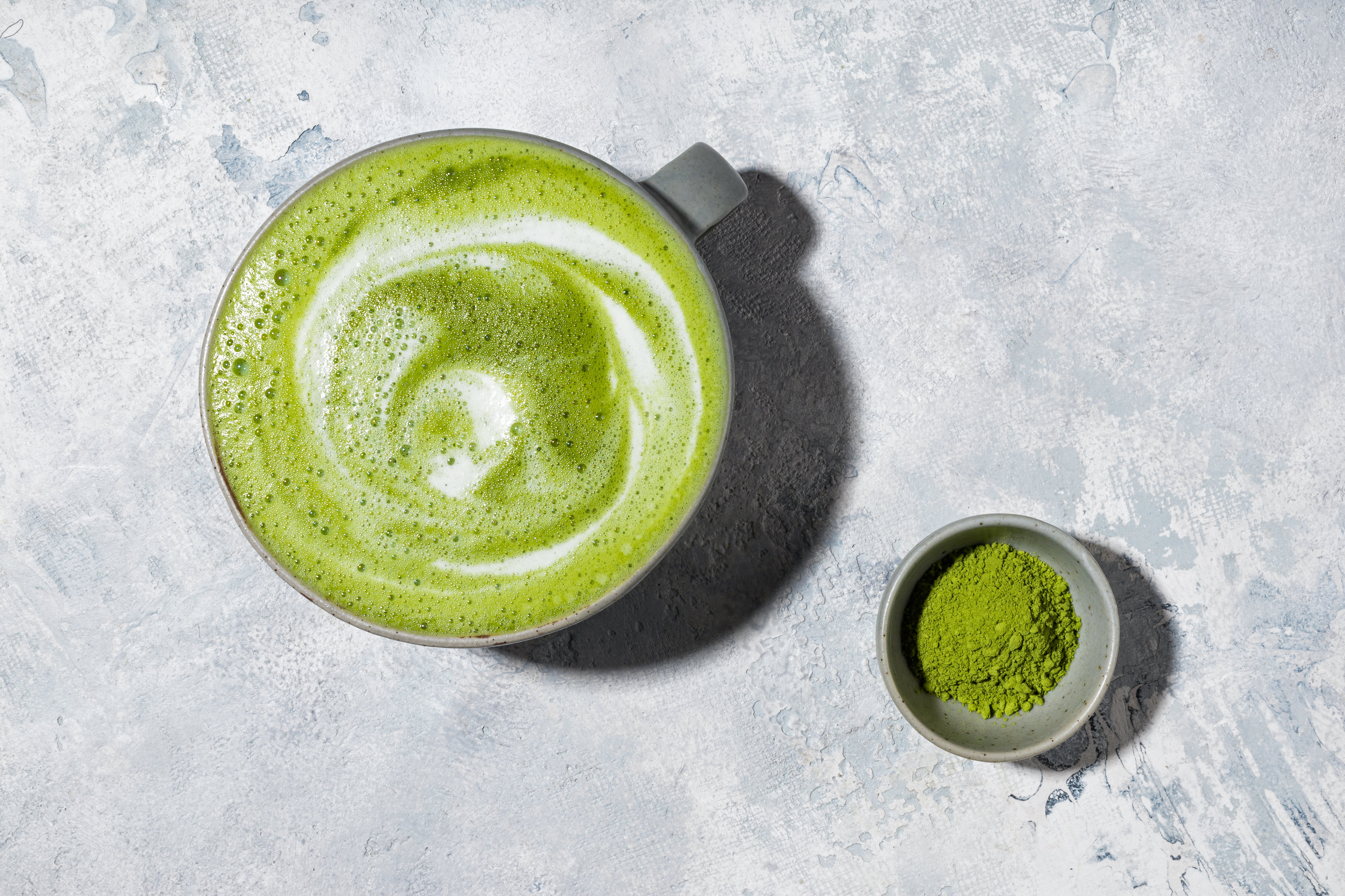 Overhead image of JOYÀ Focus Matcha Superblend latte with a small bowl of matcha powder