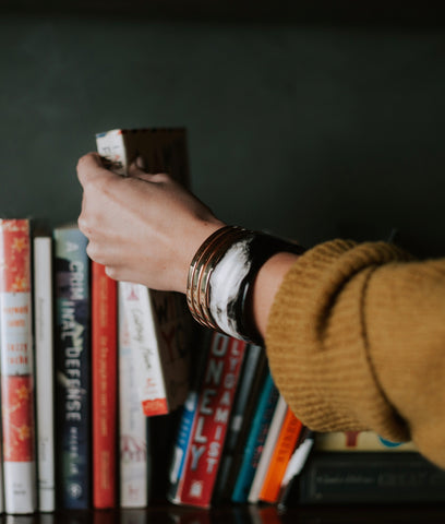 Women's hand reaching for a book on a bookshelf