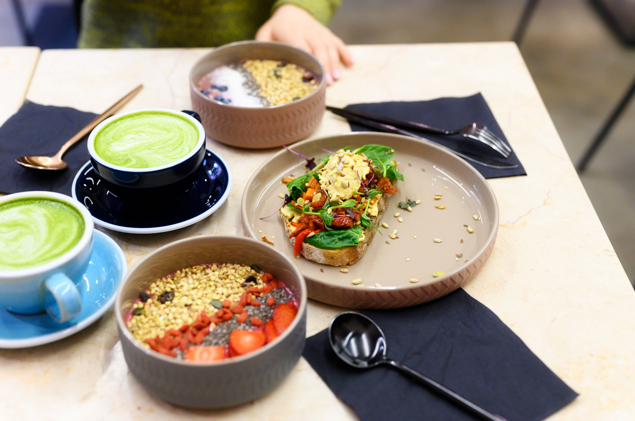 Breakfast table with smoothie bowls, fancy toast and two matcha lattes