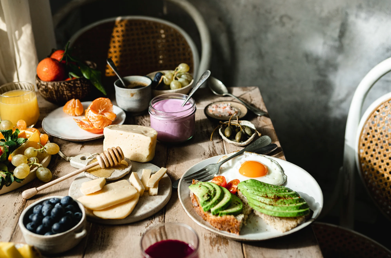 Table of breakfast foods like eggs, cheese, honey, fruit and yogurt