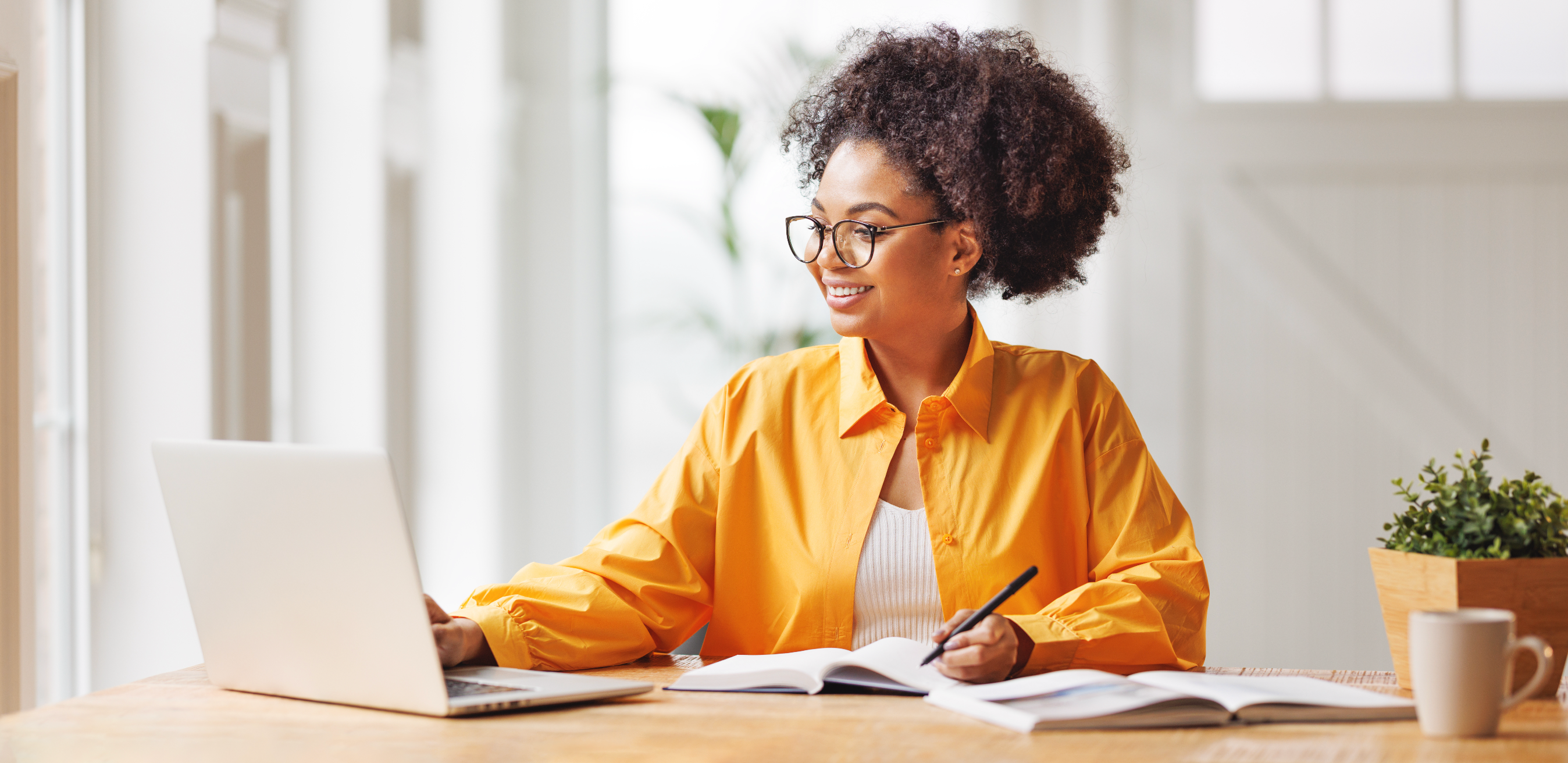 Woman with glasses working at desk on laptop