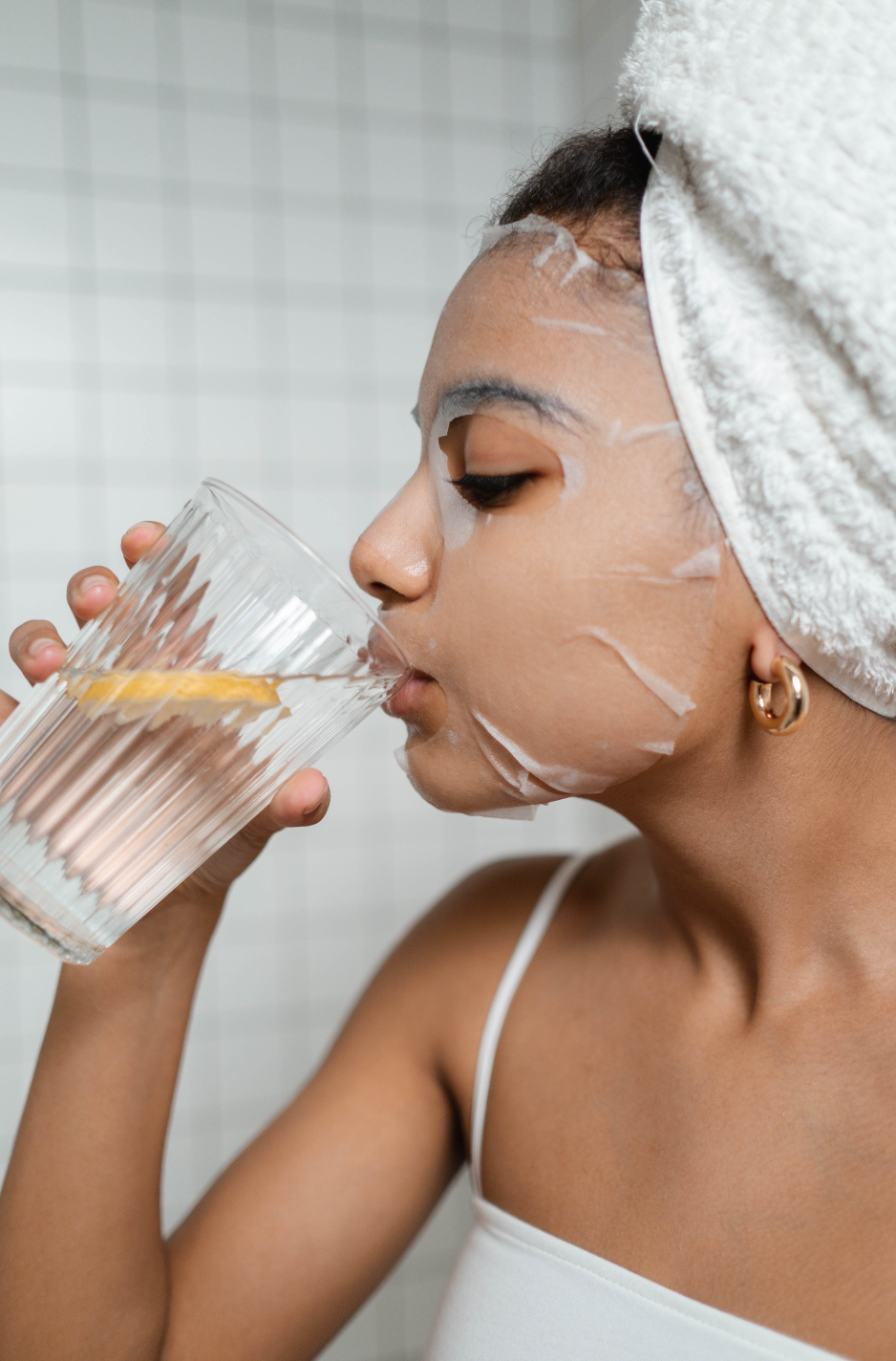 Women with sheet mask drinking water with lemon