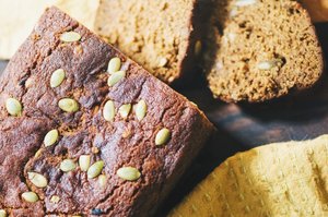 pumpkin bread loaf topped with pumpkin seeds with two peices cut off