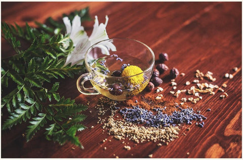 teacup on a wooden floor with wildflowers and seeds around it